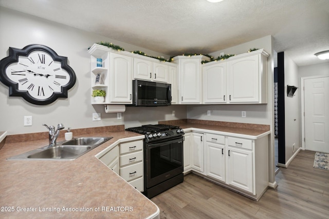 kitchen featuring gas stove, light wood finished floors, open shelves, a sink, and white cabinets