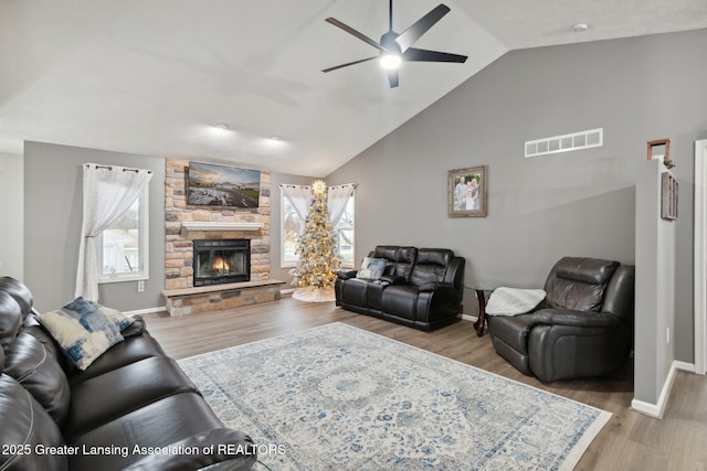 living area with visible vents, wood finished floors, baseboards, a fireplace, and lofted ceiling