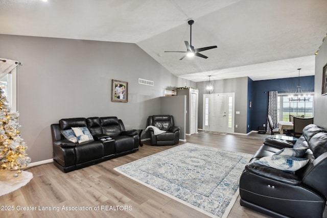 living area with visible vents, baseboards, lofted ceiling, and wood finished floors