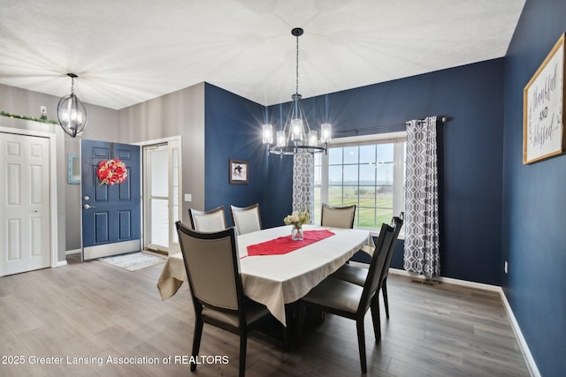 dining room with a notable chandelier, baseboards, and wood finished floors