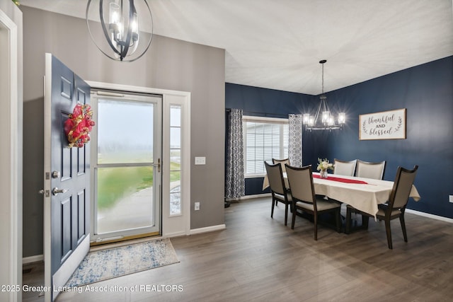 dining room with a notable chandelier, baseboards, and wood finished floors