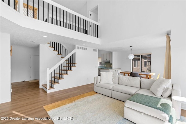 living room with visible vents, stairway, baseboards, and wood finished floors