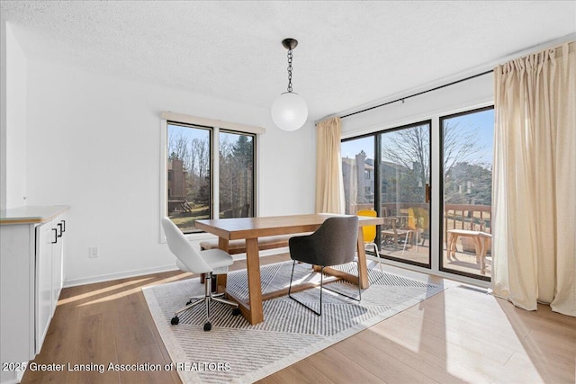 dining room with visible vents, light wood-style flooring, a textured ceiling, and baseboards