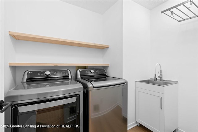 washroom featuring cabinet space, wood finished floors, separate washer and dryer, and a sink