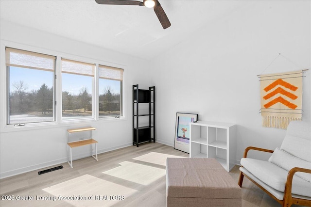 living area with visible vents, baseboards, light wood-type flooring, lofted ceiling, and a ceiling fan