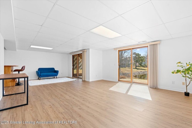 sitting room with a drop ceiling, baseboards, and light wood-style floors