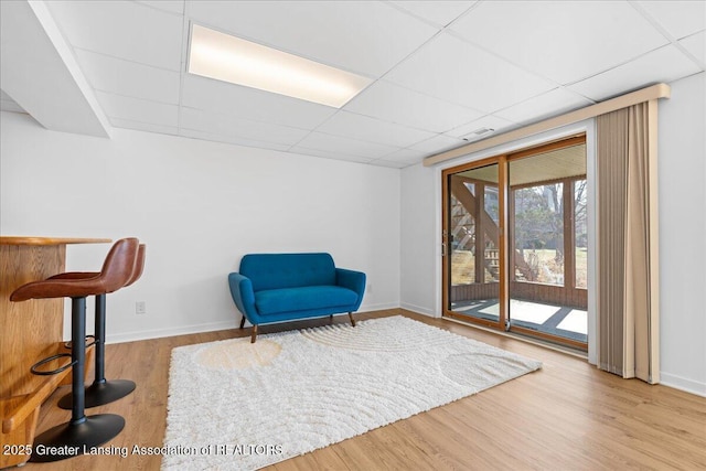 sitting room featuring visible vents, wood finished floors, baseboards, and a drop ceiling