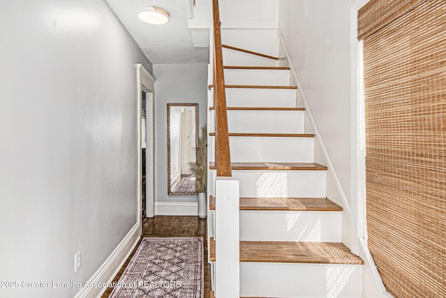 staircase featuring baseboards and wood finished floors