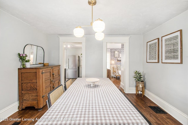 bedroom featuring dark wood-style floors, visible vents, freestanding refrigerator, and baseboards