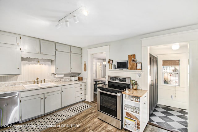 kitchen featuring tile patterned floors, appliances with stainless steel finishes, light countertops, and a sink