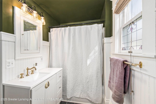 bathroom with a shower with shower curtain, a wainscoted wall, and vanity