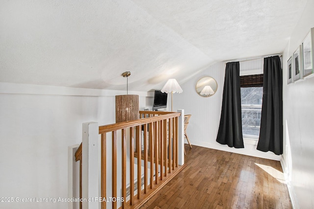 hall featuring an upstairs landing, a textured ceiling, lofted ceiling, and hardwood / wood-style floors