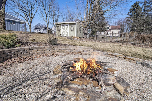 view of yard with an outbuilding, a shed, a fire pit, and fence