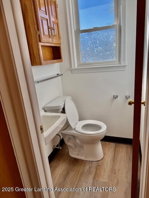 bathroom with a sink, baseboards, toilet, and wood finished floors