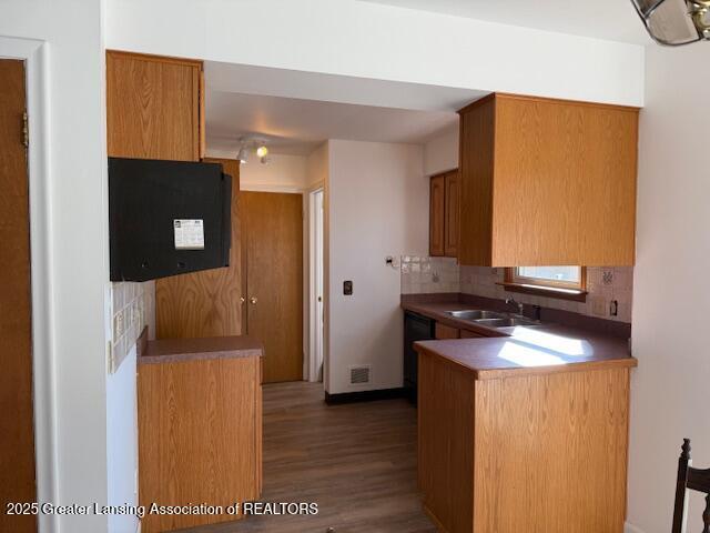 kitchen featuring brown cabinetry, visible vents, a peninsula, and a sink