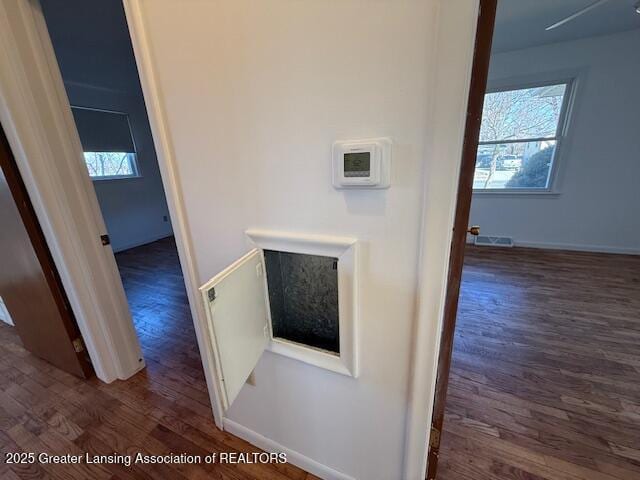 corridor featuring wood finished floors, visible vents, and baseboards