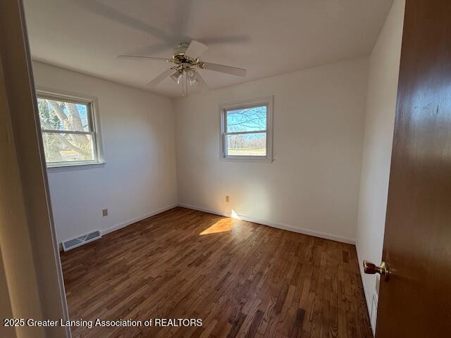 unfurnished room featuring visible vents, baseboards, wood finished floors, and a ceiling fan