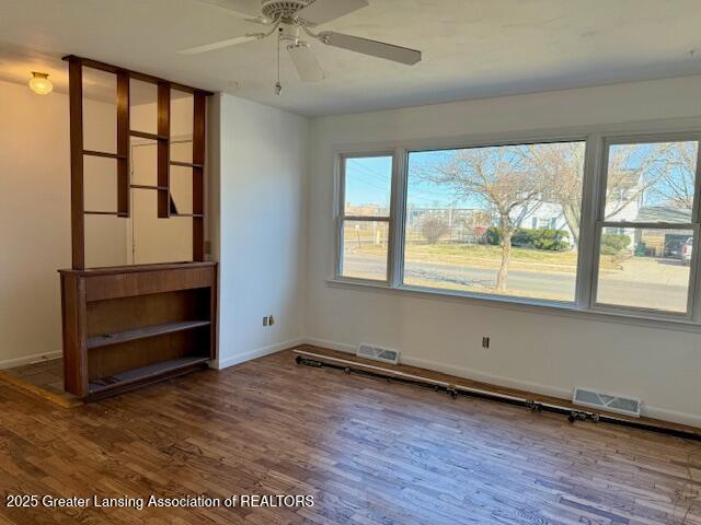 empty room featuring visible vents, baseboards, and wood finished floors