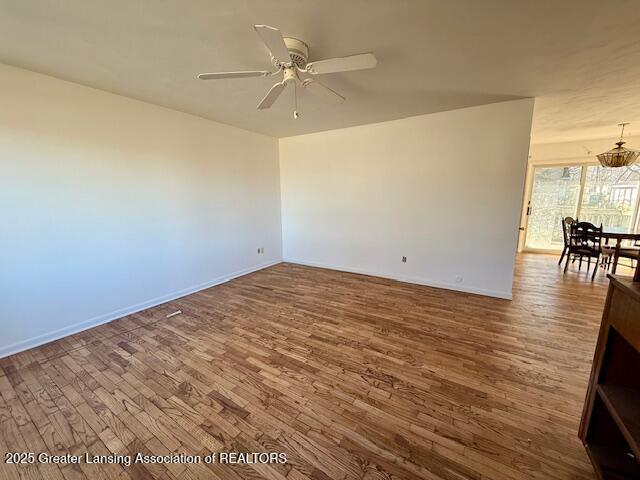 empty room featuring a ceiling fan, wood finished floors, and baseboards