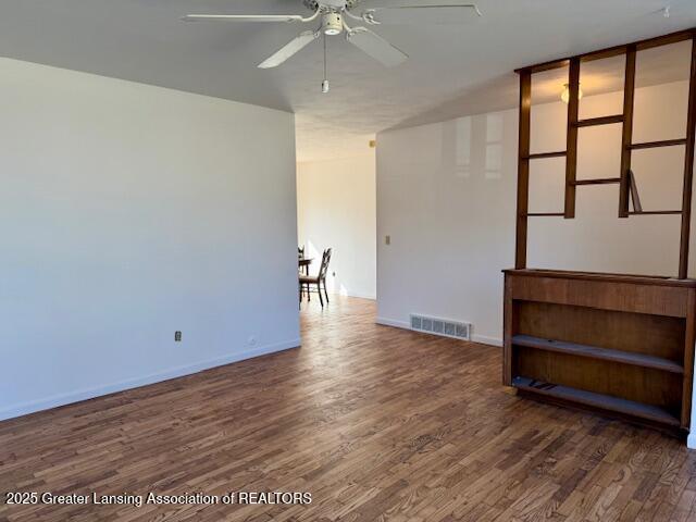 empty room featuring visible vents, baseboards, ceiling fan, and wood finished floors