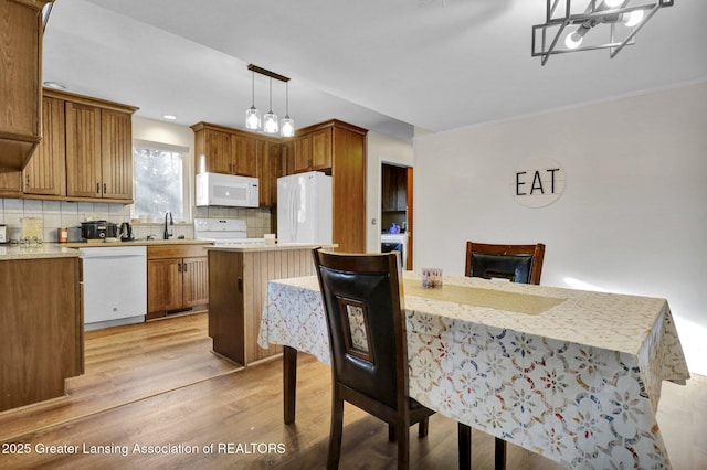 kitchen featuring decorative backsplash, brown cabinets, white appliances, and light wood-type flooring