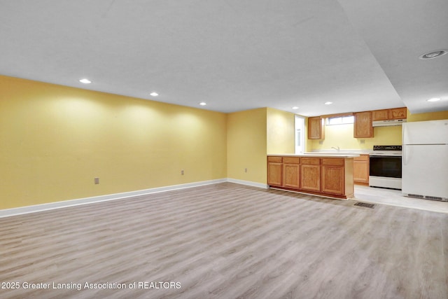 interior space with white appliances, open floor plan, baseboards, and light wood finished floors