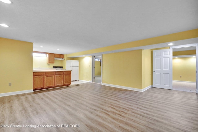 unfurnished living room with recessed lighting, light wood-style flooring, and baseboards