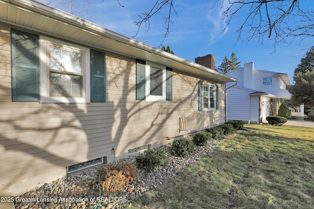 view of side of home with a yard and a chimney