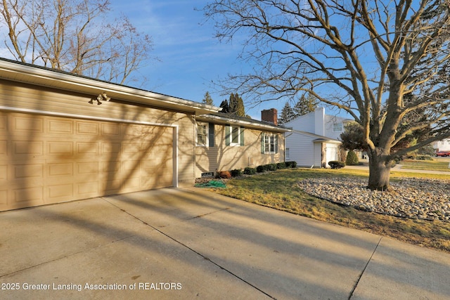 single story home featuring brick siding, driveway, a chimney, and a garage