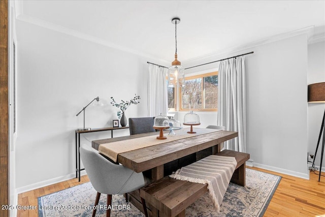 dining room with crown molding, baseboards, light wood-type flooring, and a chandelier