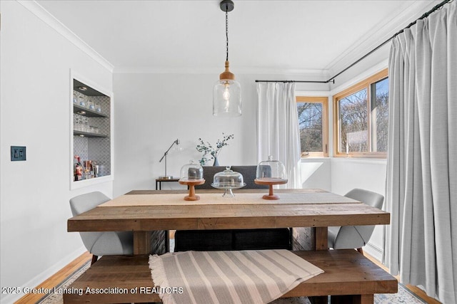 dining space featuring built in shelves, baseboards, wood finished floors, and crown molding