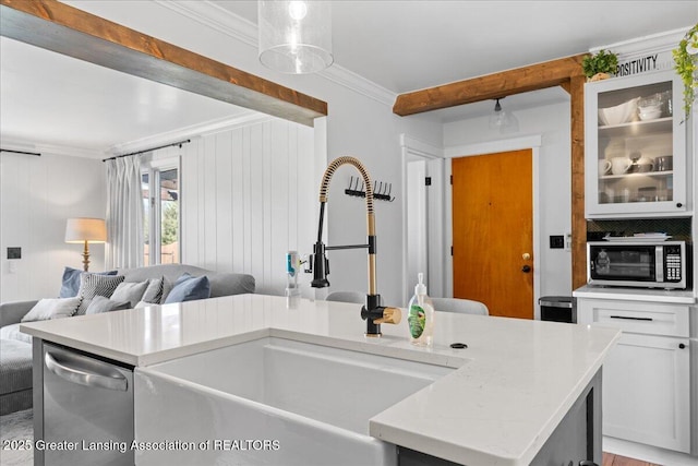 kitchen with crown molding, light countertops, stainless steel appliances, and a sink