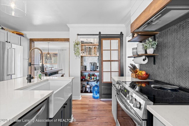 kitchen with light countertops, ornamental molding, range hood, light wood-style floors, and stainless steel appliances