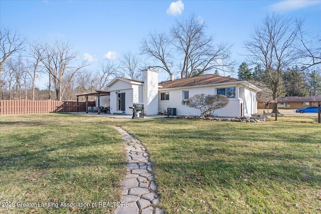 rear view of property featuring fence, central AC, a chimney, a yard, and a patio