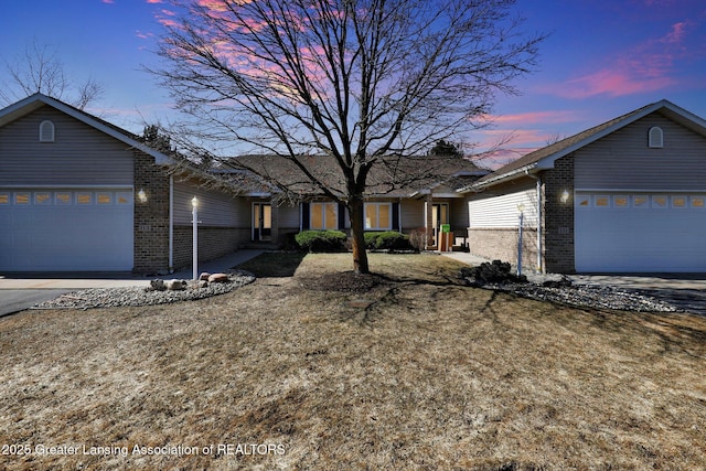 ranch-style home with driveway, brick siding, and an attached garage