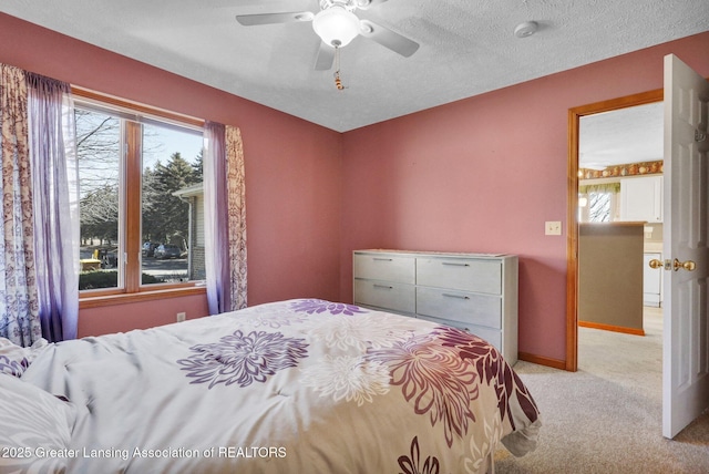 bedroom featuring a textured ceiling, multiple windows, baseboards, and light carpet