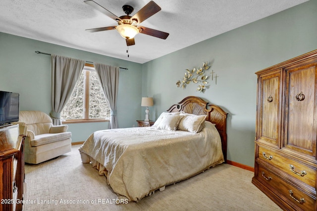 bedroom featuring light colored carpet, a textured ceiling, baseboards, and a ceiling fan