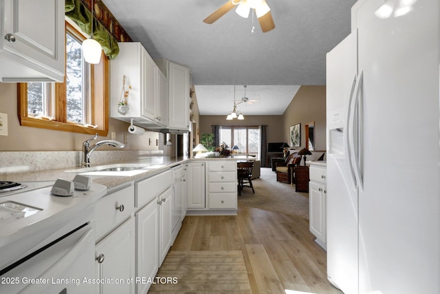 kitchen with white appliances, a peninsula, a sink, light countertops, and white cabinetry