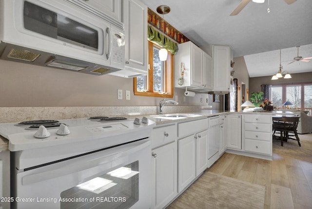 kitchen featuring white appliances, a peninsula, a sink, light countertops, and white cabinets