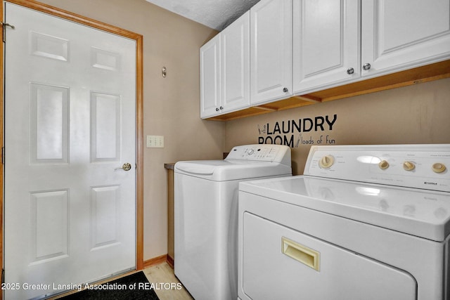 clothes washing area with baseboards, cabinet space, and washing machine and dryer