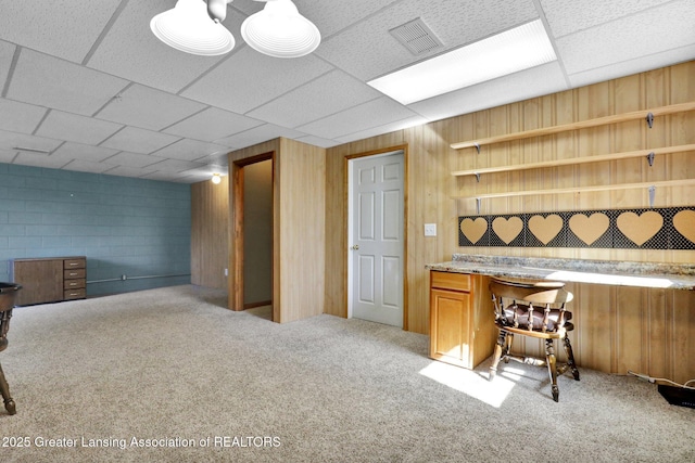 bar with concrete block wall, carpet flooring, visible vents, and a drop ceiling