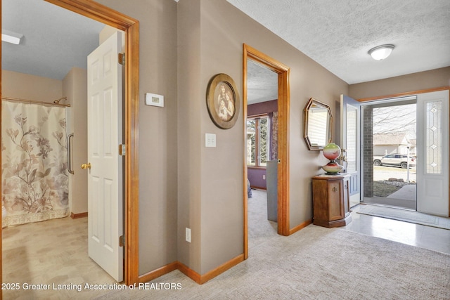 entrance foyer with light carpet, a textured ceiling, and baseboards