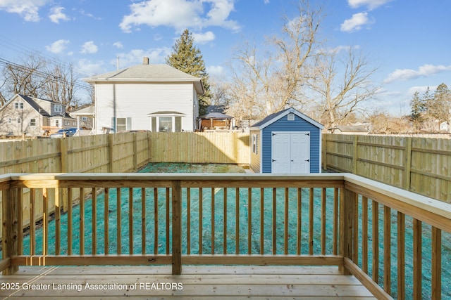 wooden terrace with an outbuilding, a fenced backyard, a storage unit, a lawn, and a residential view