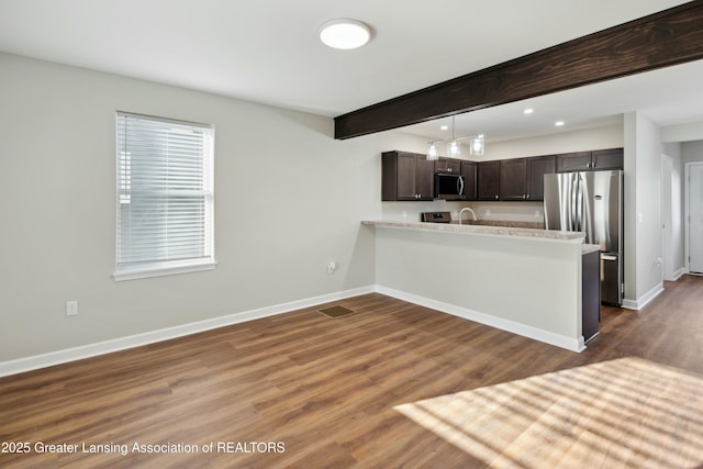 kitchen with dark brown cabinets, baseboards, beamed ceiling, light countertops, and appliances with stainless steel finishes