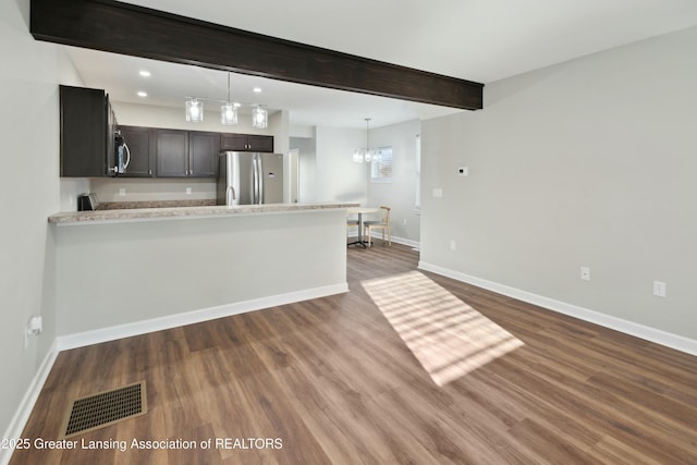 kitchen featuring baseboards, visible vents, light countertops, appliances with stainless steel finishes, and beamed ceiling