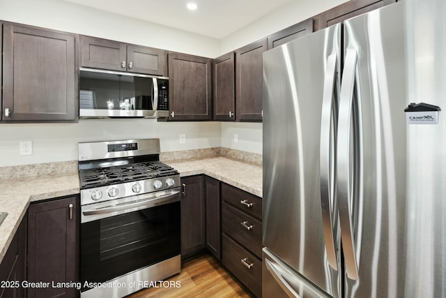 kitchen featuring dark brown cabinets, appliances with stainless steel finishes, and light wood-type flooring