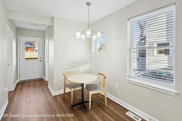 dining space featuring visible vents, baseboards, dark wood-type flooring, and an inviting chandelier