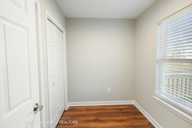 unfurnished bedroom featuring a closet, dark wood-style floors, and baseboards