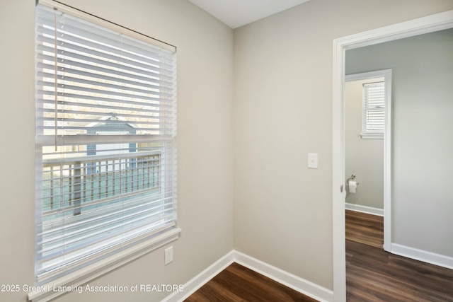 spare room featuring baseboards and dark wood-style flooring