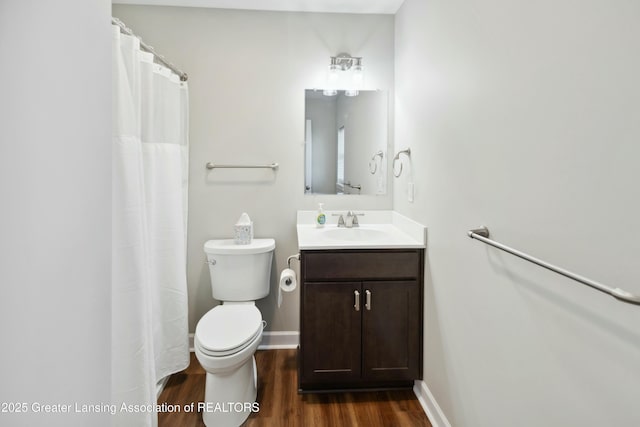 bathroom with vanity, toilet, wood finished floors, and baseboards